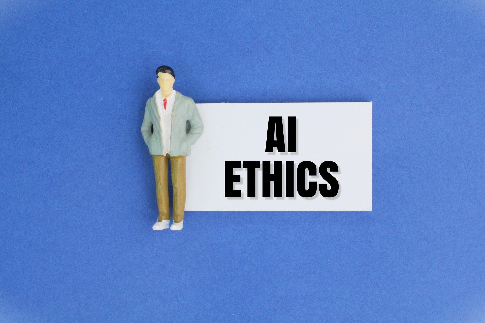 miniature people and paper with the word AI ETHICS. Ethical concepts for artificial intelligence